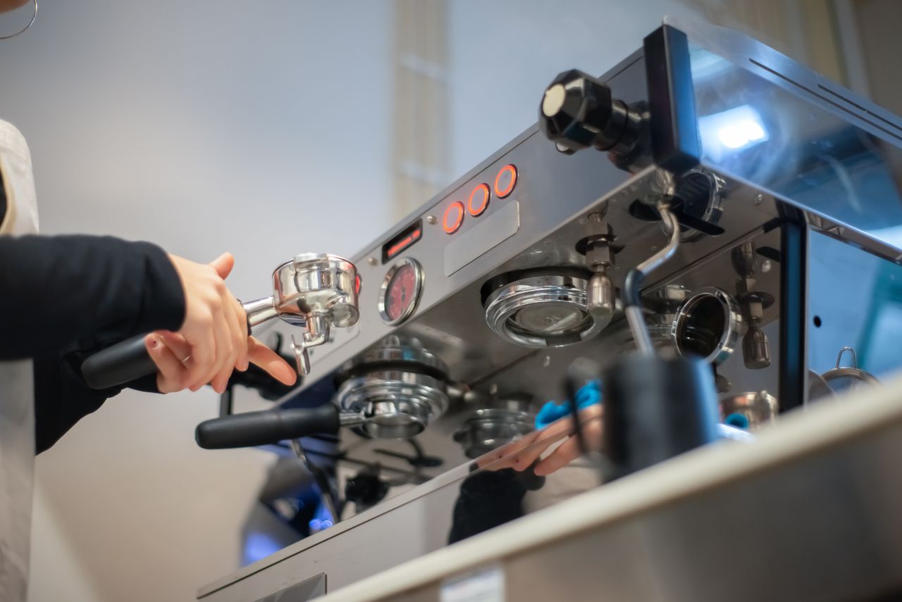 A barista prepares coffee on a modern espresso machine in a cozy café.